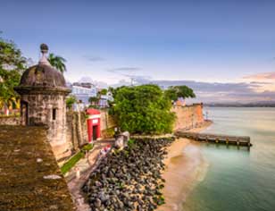 Antigua garita de piedra junto a una muralla costera y el mar.