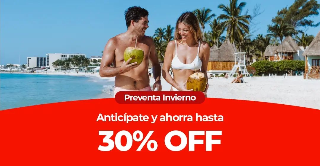 Pareja sonriente con cocos en una playa de arena con palmeras.