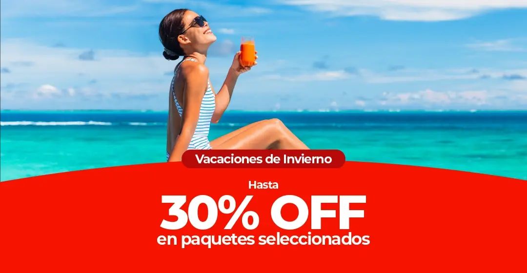 Una mujer en traje de baño sentada en una playa tropical con una bebida.