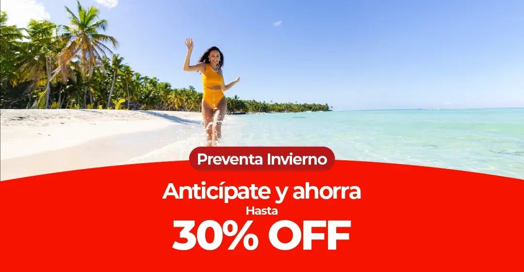 Mujer sonriente en traje de baño amarillo corriendo en una playa tropical.