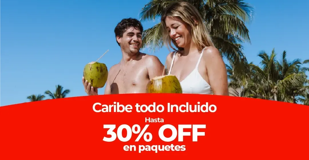 Una pareja sonríe en la playa sosteniendo cocos bajo palmeras.