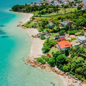Vista aérea de costa con playas, agua clara y casas rodeadas de vegetación.