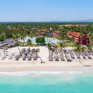 Resort tropical con playa, piscinas y edificios junto al mar.