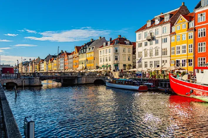 Park Güell mosaic bench, gatehouse, and city view under blue sky.