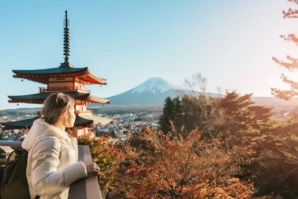 Una mujer observa una pagoda roja, el Monte Fuji y la ciudad.