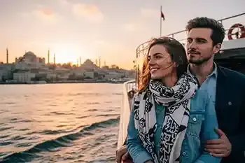 Una pareja en un barco con la ciudad de Estambul al atardecer.